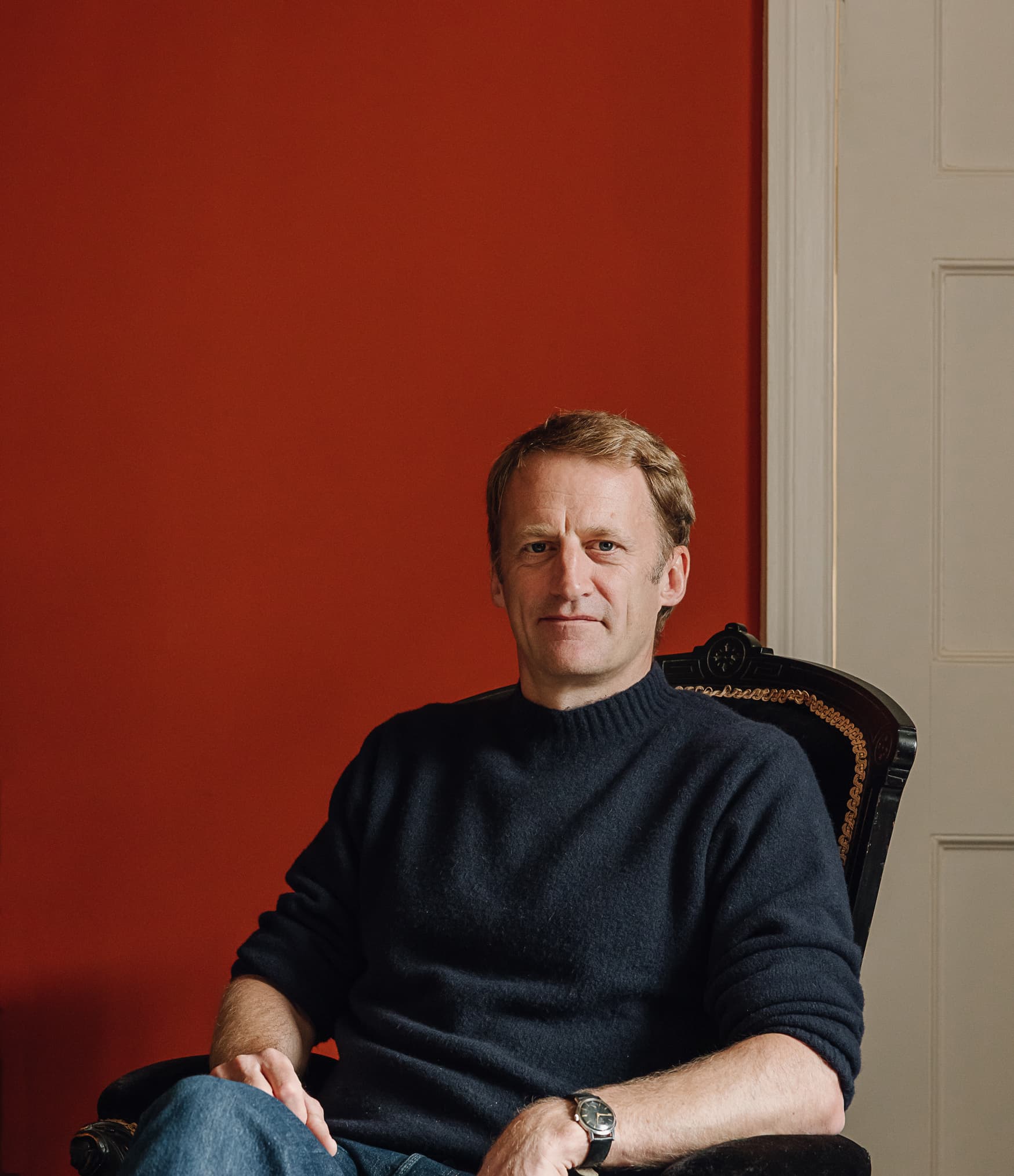 Guy Tobin seated against a deep red wall